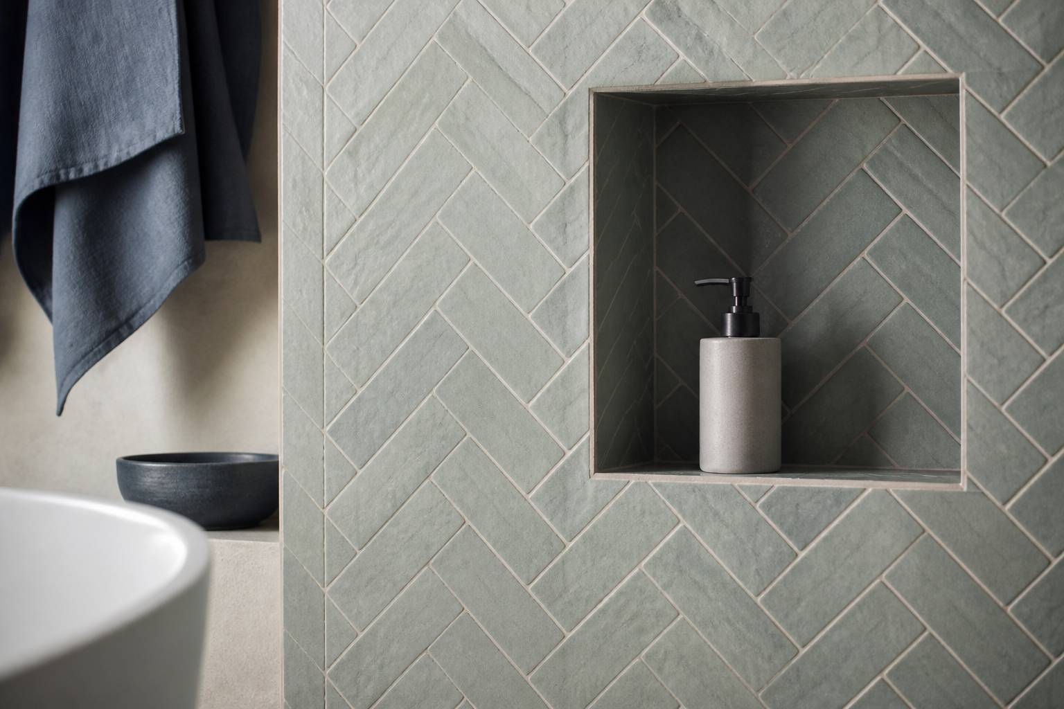 Mur de salle de bains en carreaux texturés vert-de-gris posés en chevrons
