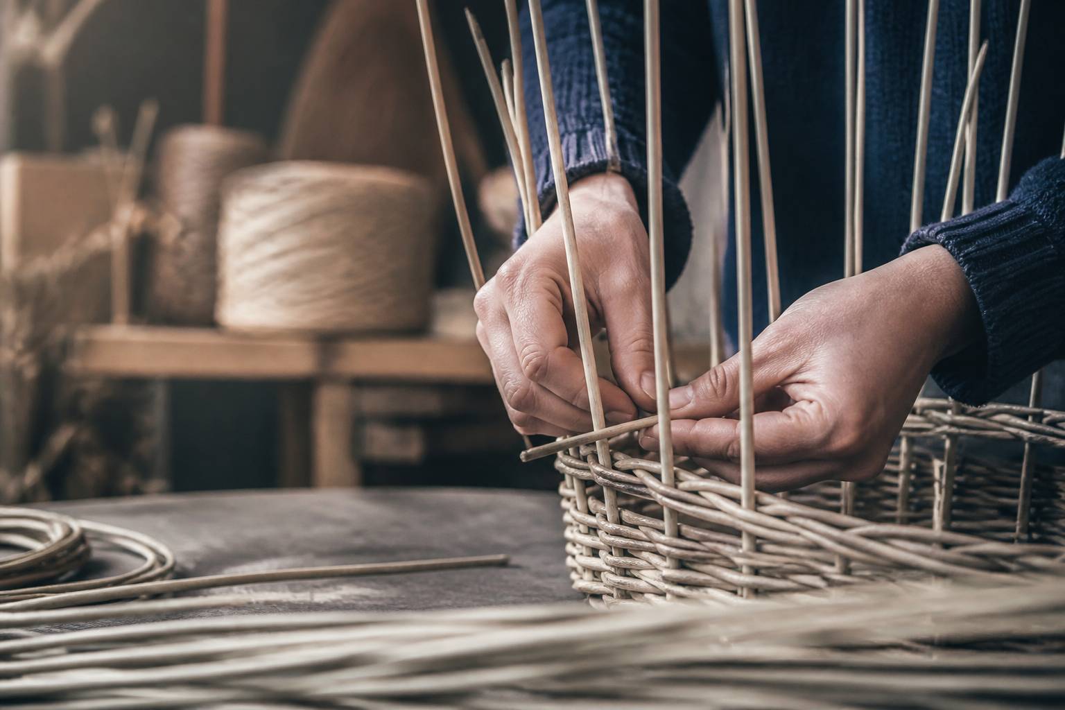 Mains d'artisan tressant des brins d'osier