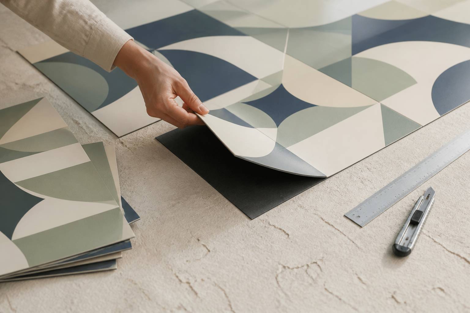 Échantillons de carrelage adhésif à motifs géométriques posés au sol